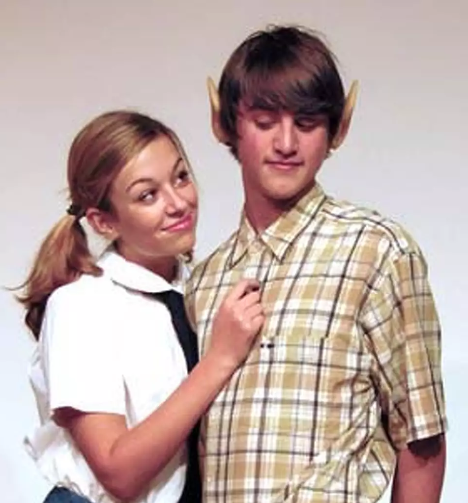 Two young people in costume with pointed ears, woman in white shirt with tie, man in plaid shirt, posing together