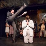 Bat Boy - Theater performance with actors in period costumes on stage, including performers in white and dark clothing