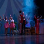 Theater performance with actors in colorful costumes on stage under dramatic blue lighting during live show