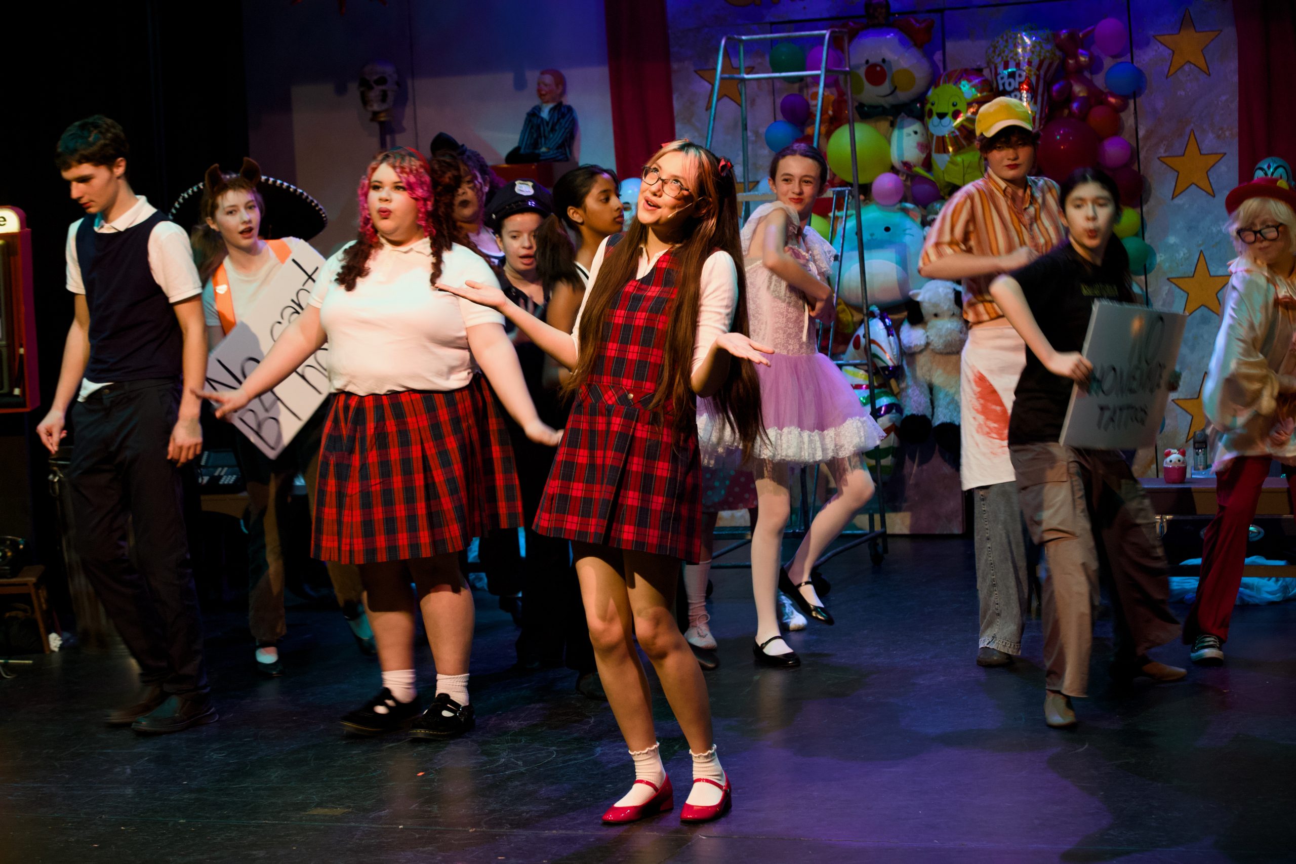 Young performers in school uniforms and costumes on stage during a colorful musical theater production