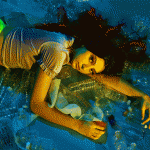 Little Mermaid - Underwater photographer with camera taking photos of marine life in deep blue ocean waters